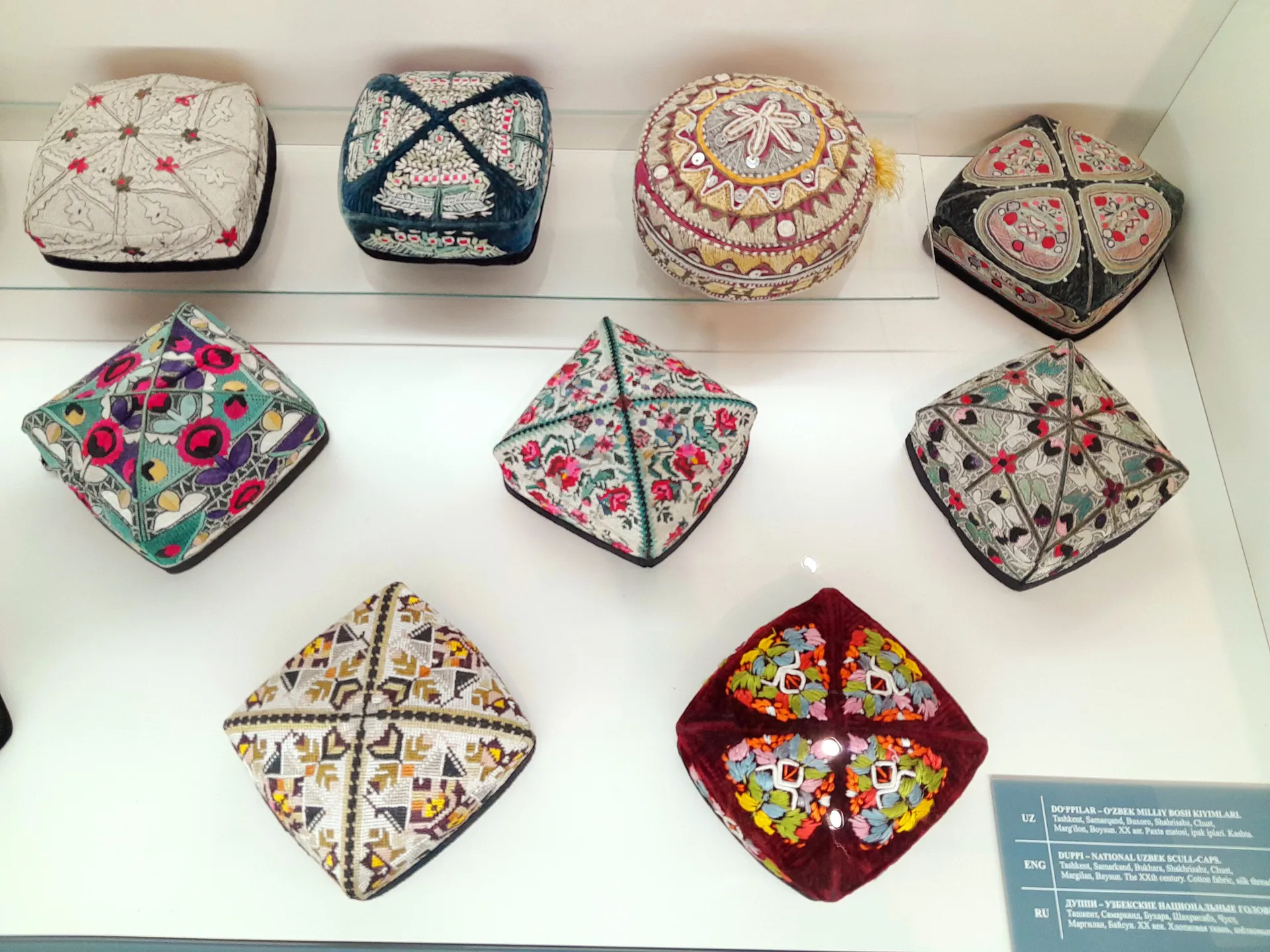 Embroidered doppi skullcaps. Their patterns tell where they come from — the white pepper-pod motif of Chust is the most famous.