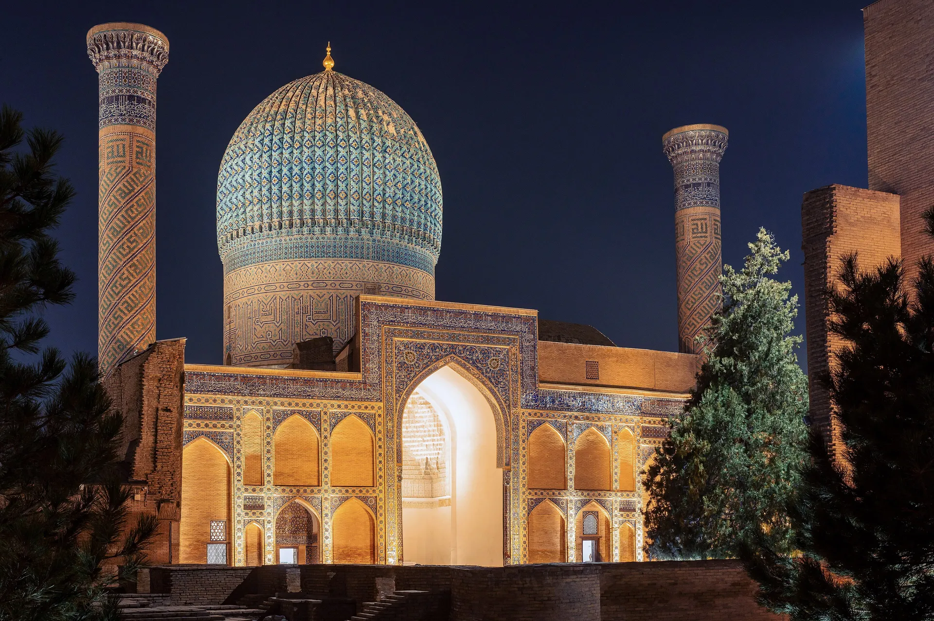 The ribbed turquoise dome over the tomb of Amir Temur, lit up after dark in Samarkand.