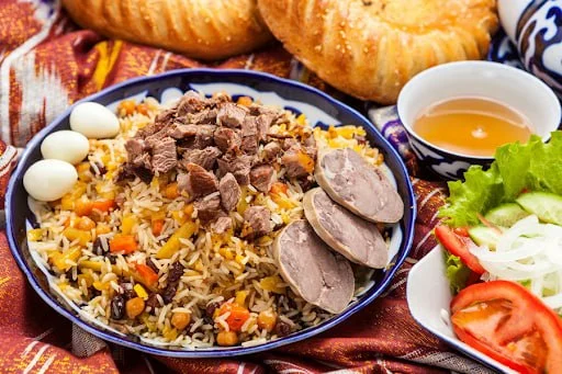 طاهٍ يقلّب الأرزّ فوق الزيرفاك في قِدر حديدية واسعة بأحد مطاعم البلوف في طشقند.