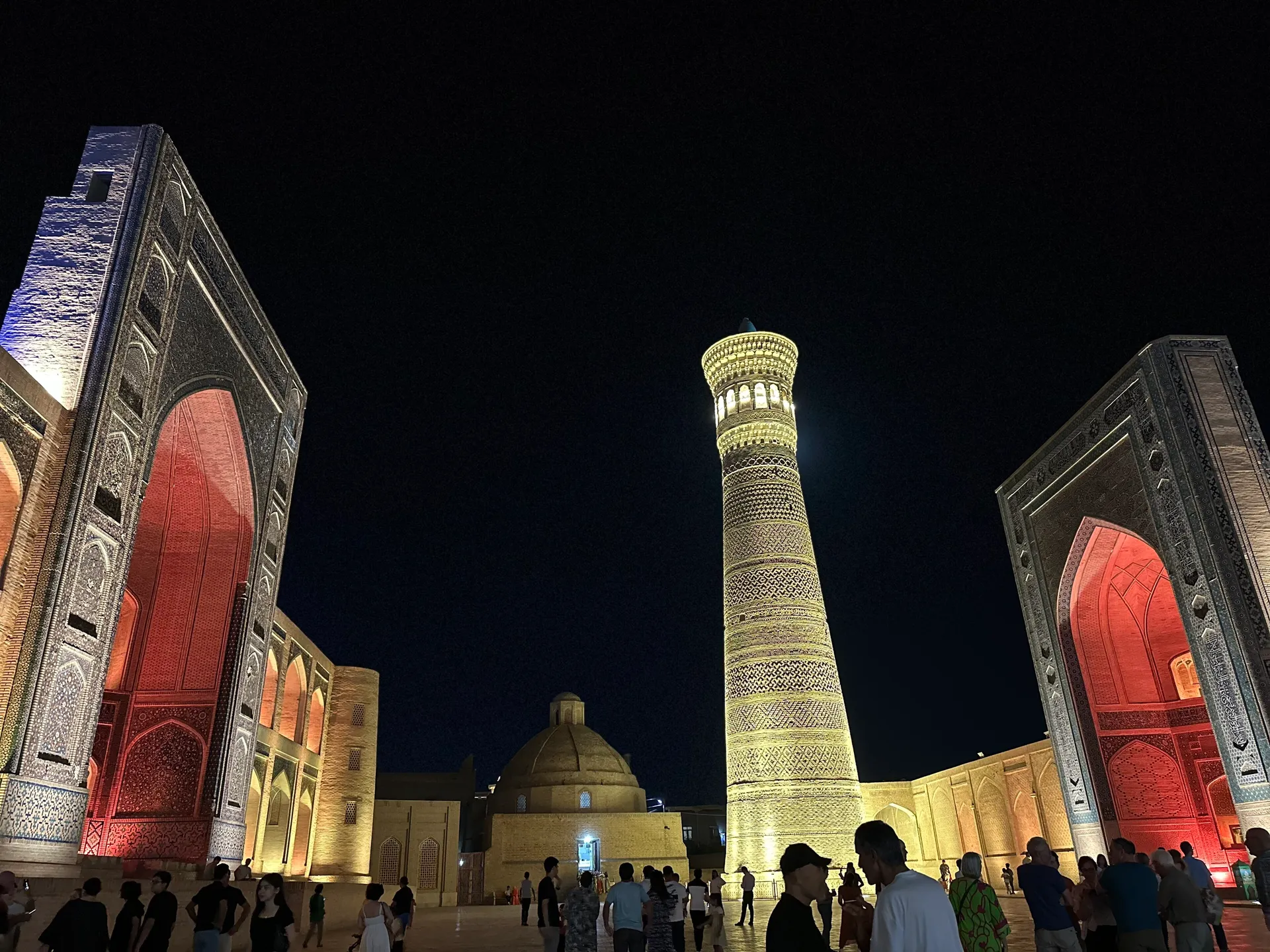 The Kalyan Minaret between the lit portals of the Kalyan Mosque and the Mir-i-Arab madrasa, the heart of Bukhara after dark.