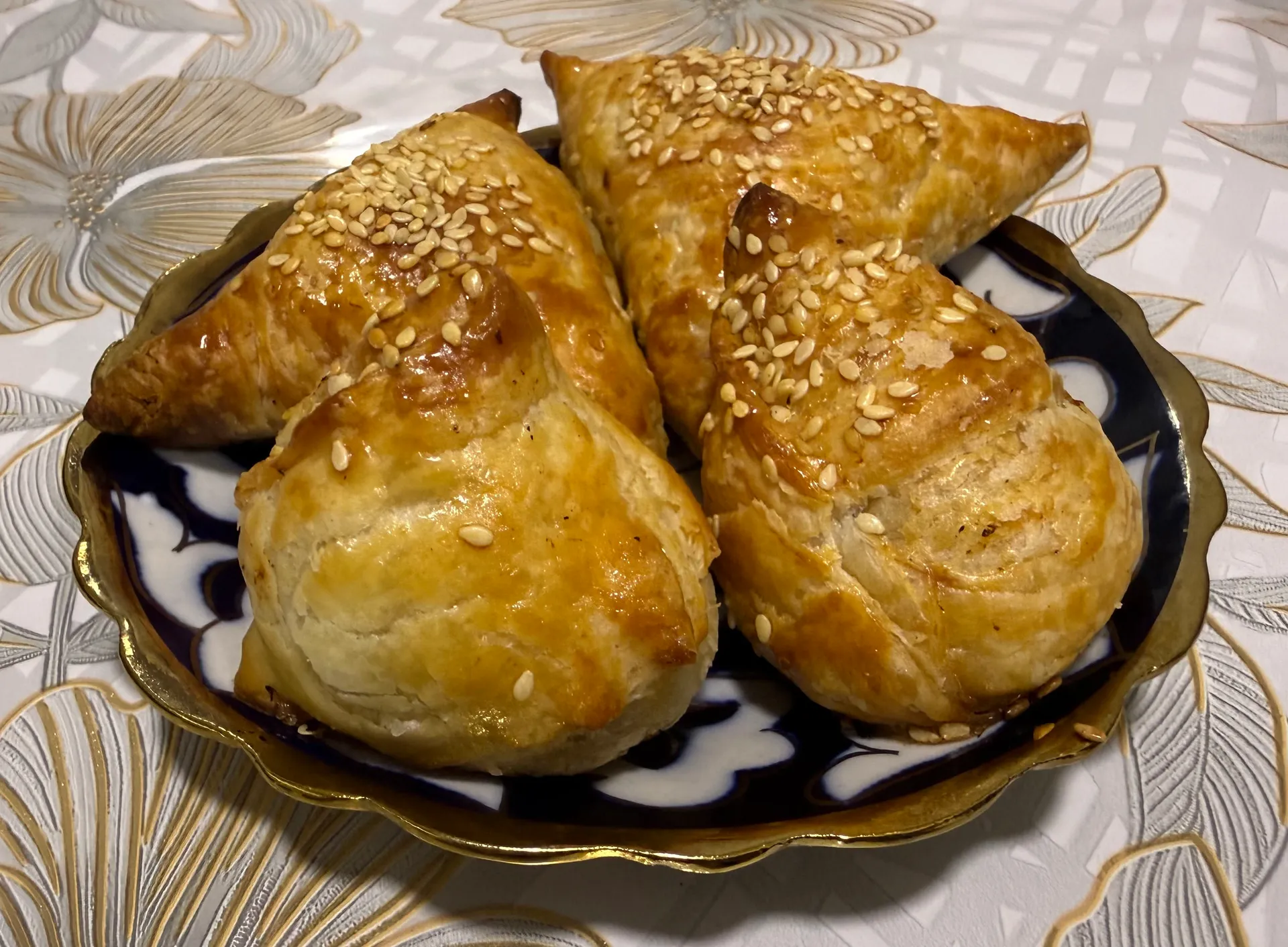 Homemade samsa in Tashkent: flaky pastry filled with lamb, onion and fat, sprinkled with sesame and baked golden.