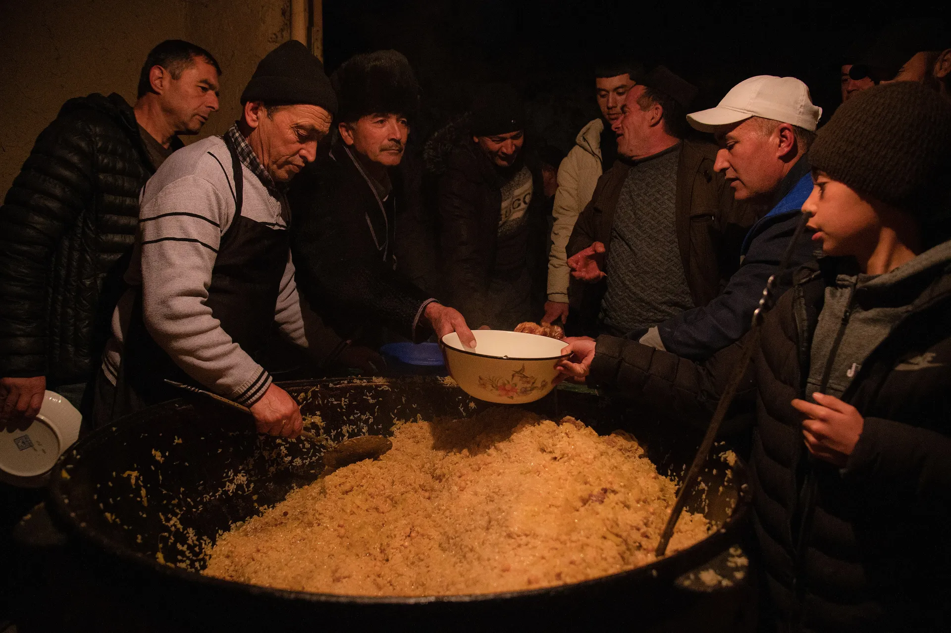 Men serving plov from a huge kazan at a wedding. No Uzbek wedding is complete without it, and the morning plov feeds the whole neighbourhood.
